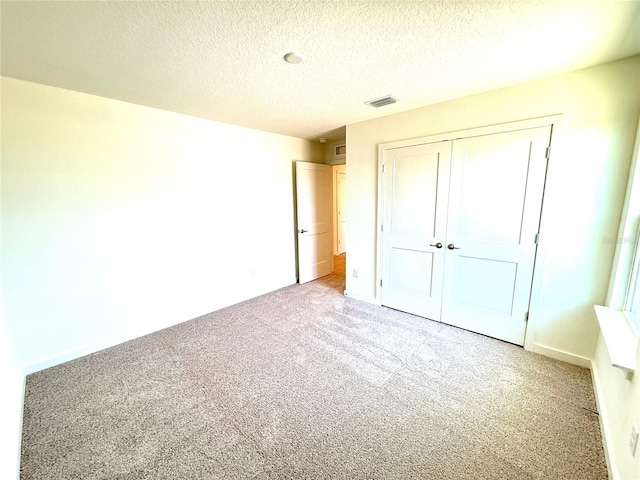 unfurnished bedroom featuring a closet, light carpet, and a textured ceiling