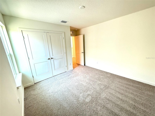 unfurnished bedroom featuring a closet, light colored carpet, and a textured ceiling