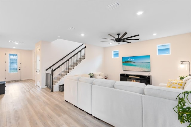 living room featuring ceiling fan, light wood-type flooring, and a fireplace