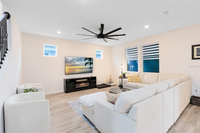 living room featuring ceiling fan, light hardwood / wood-style floors, and a fireplace