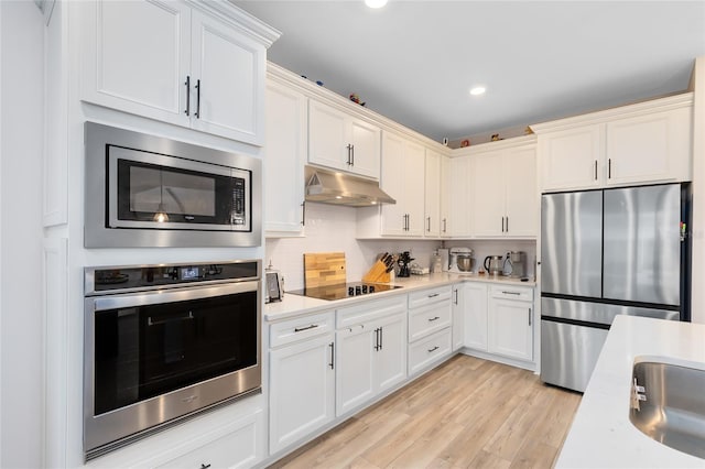 kitchen featuring backsplash, sink, appliances with stainless steel finishes, and light hardwood / wood-style flooring