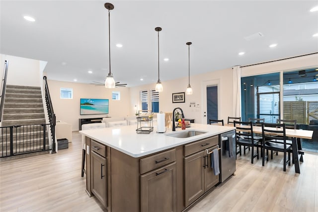 kitchen with ceiling fan, sink, decorative light fixtures, dishwasher, and an island with sink