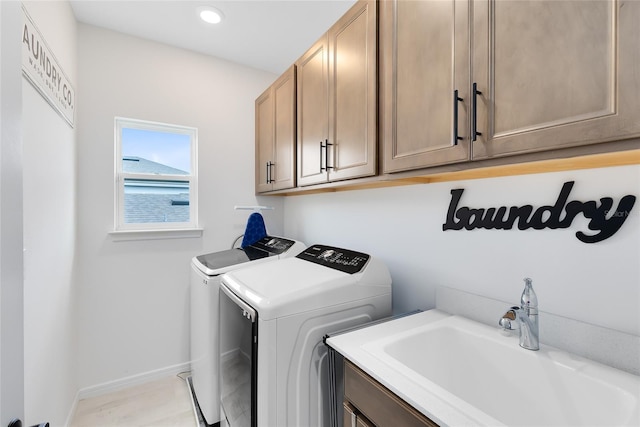 clothes washing area featuring cabinets, washer and dryer, and sink