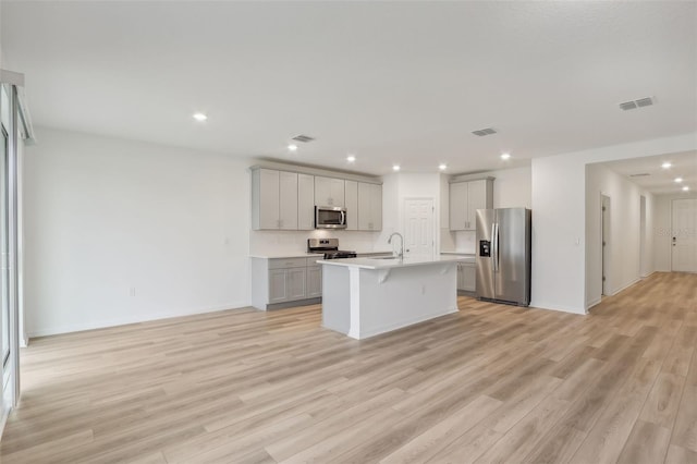 kitchen featuring a kitchen island with sink, sink, light hardwood / wood-style flooring, gray cabinets, and stainless steel appliances