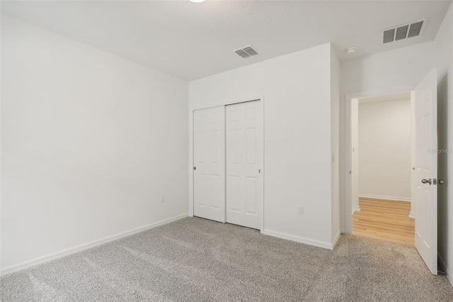 unfurnished bedroom featuring a closet and light colored carpet