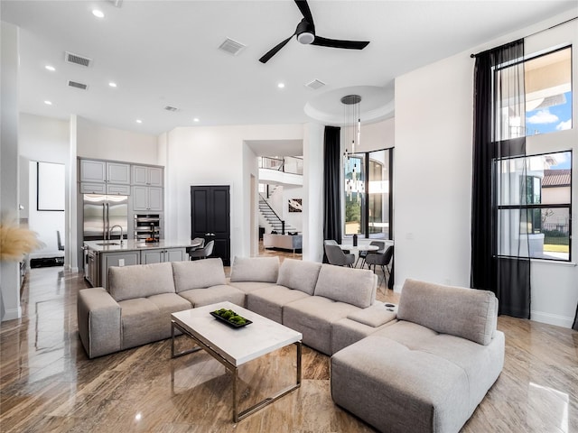 living room featuring ceiling fan with notable chandelier and sink