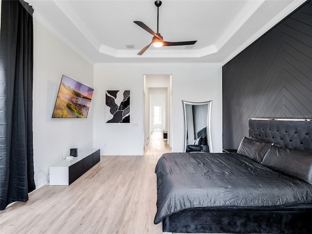 bedroom with light hardwood / wood-style flooring, ornamental molding, ceiling fan, and a raised ceiling