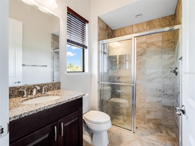 bathroom featuring vanity, an enclosed shower, and toilet