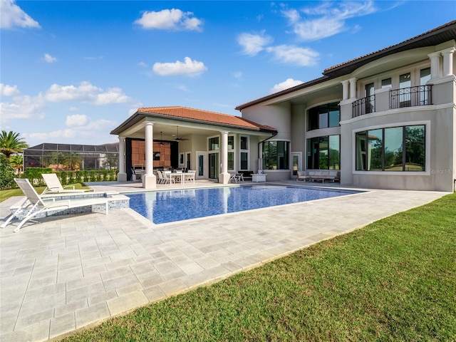 view of pool featuring a jacuzzi, ceiling fan, a patio area, and a lawn