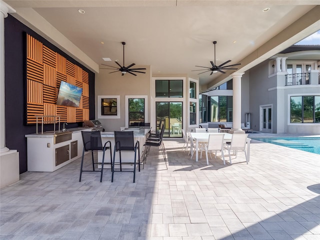 view of patio / terrace featuring ceiling fan, a bar, and exterior kitchen