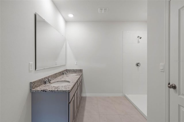 bathroom with a tile shower, vanity, and tile patterned floors