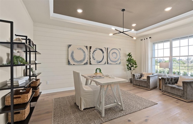 dining area featuring a notable chandelier, hardwood / wood-style flooring, and a raised ceiling