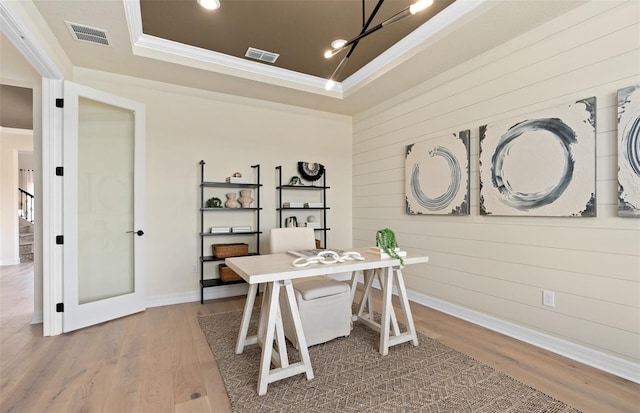 office space with hardwood / wood-style floors, a tray ceiling, ornamental molding, and wood walls