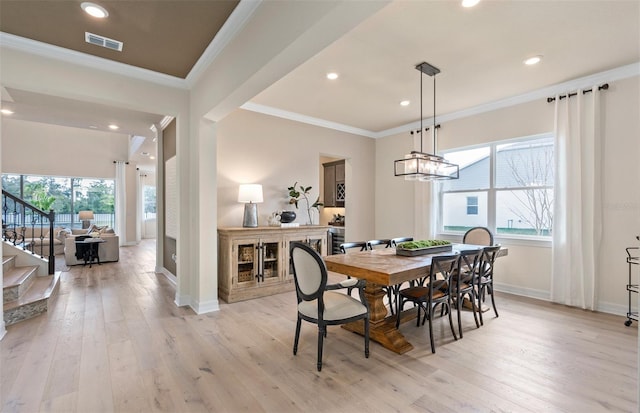 dining room with ornamental molding, a chandelier, light hardwood / wood-style floors, and plenty of natural light