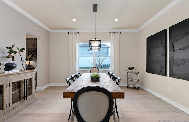 dining area with crown molding, light hardwood / wood-style flooring, and an inviting chandelier