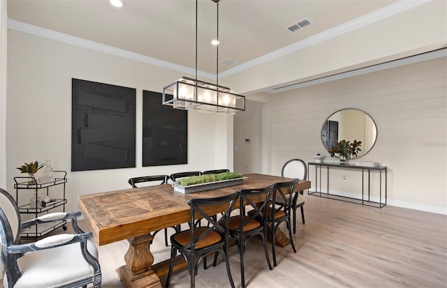 dining room with light wood-type flooring, an inviting chandelier, and crown molding