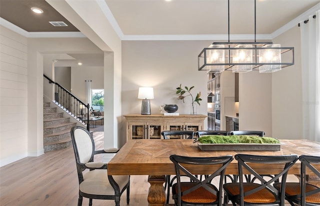 dining room with crown molding, an inviting chandelier, and light wood-type flooring