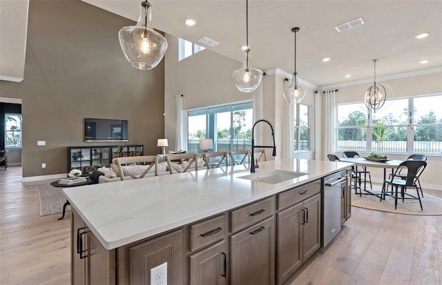 kitchen featuring light hardwood / wood-style flooring, sink, a center island with sink, a high ceiling, and decorative light fixtures