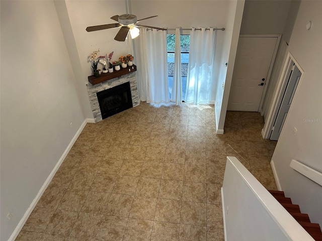 unfurnished living room featuring a fireplace, light tile patterned floors, a towering ceiling, and ceiling fan