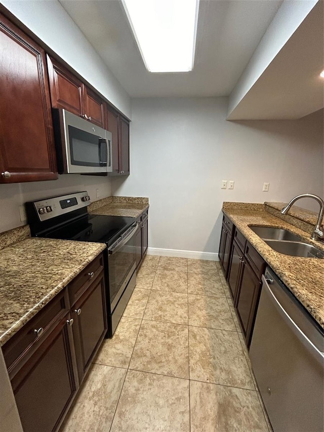 kitchen featuring appliances with stainless steel finishes, stone countertops, light tile patterned floors, and sink