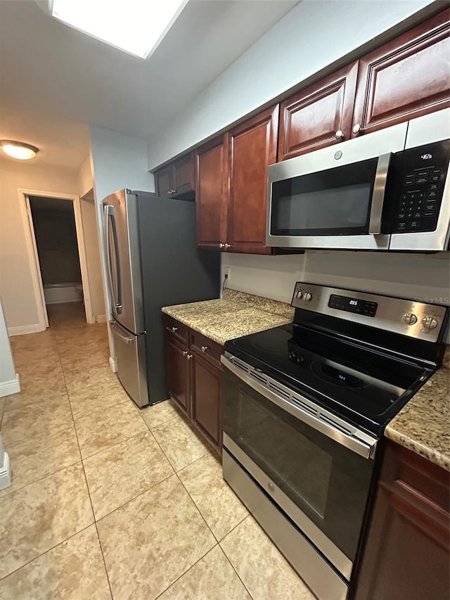 kitchen featuring light stone counters, light tile patterned flooring, and appliances with stainless steel finishes