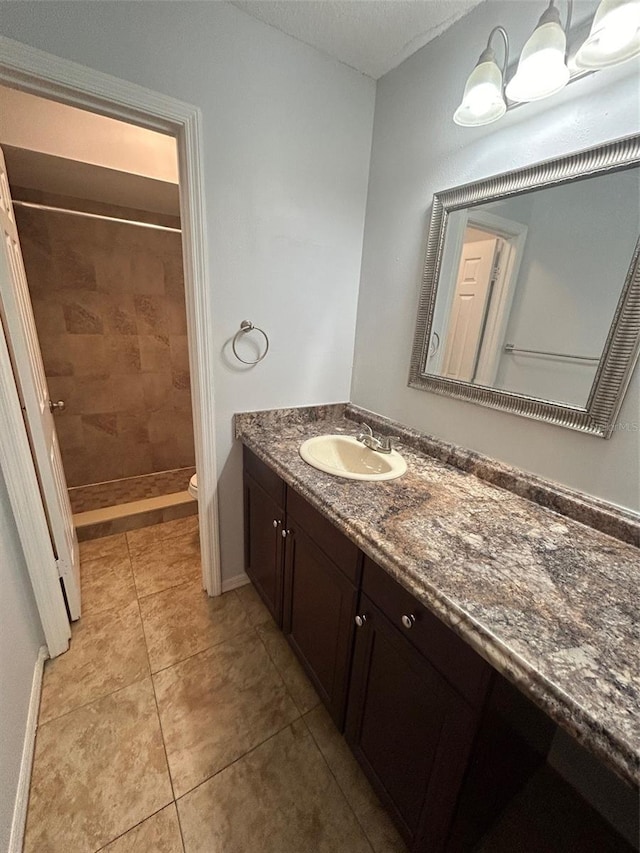 bathroom featuring vanity, tile patterned flooring, toilet, tiled shower, and a textured ceiling