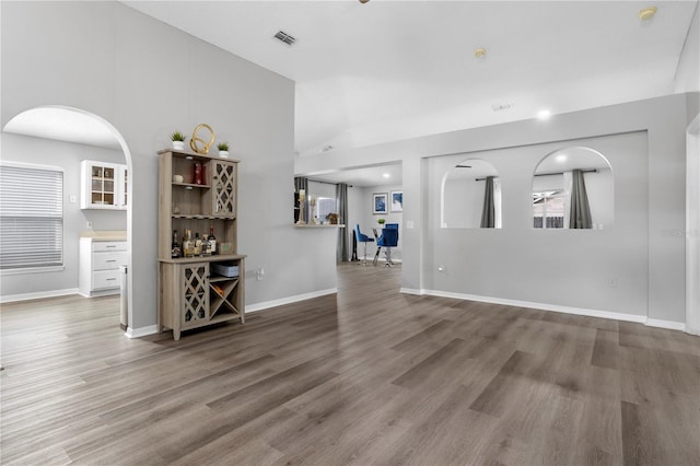 unfurnished living room featuring hardwood / wood-style flooring, lofted ceiling, and bar area