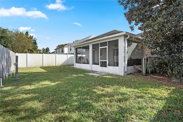 rear view of house featuring a yard and a sunroom