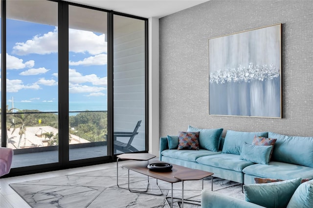 living room featuring a healthy amount of sunlight, light wood-type flooring, a wall of windows, and a water view