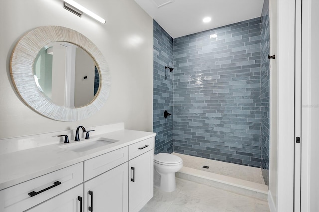 bathroom with tiled shower, vanity, and toilet