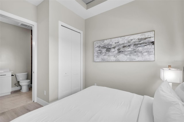 bedroom featuring ensuite bathroom, light hardwood / wood-style flooring, and a closet