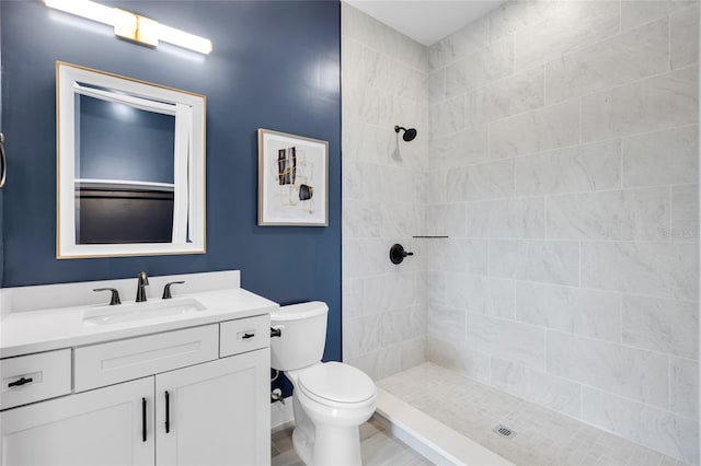 bathroom with vanity, toilet, and a tile shower