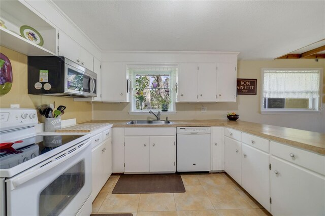 kitchen featuring white cabinets, light tile patterned flooring, white appliances, and sink