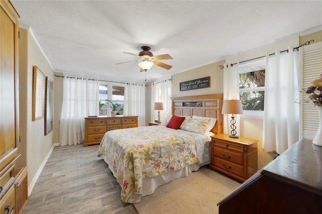 bedroom with ceiling fan, light wood-type flooring, and multiple windows