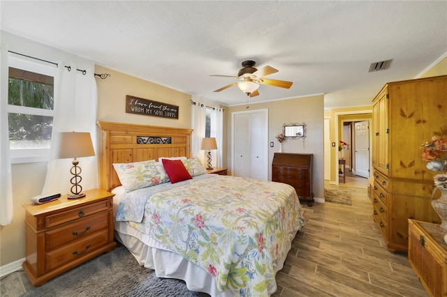 bedroom featuring a textured ceiling, crown molding, ceiling fan, and dark wood-type flooring