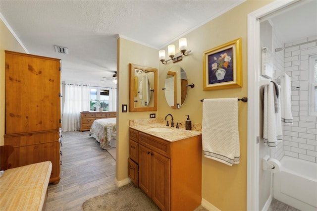 bathroom featuring vanity, wood-type flooring, tiled shower / bath combo, and ornamental molding