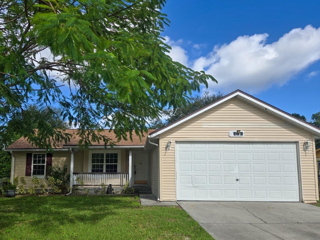 ranch-style home featuring a front lawn, a porch, and a garage