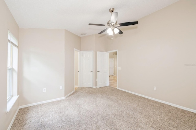 unfurnished bedroom featuring ceiling fan, light carpet, and multiple windows