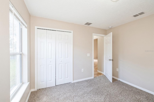 unfurnished bedroom featuring a closet, carpet, and a textured ceiling