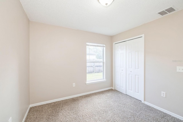 unfurnished bedroom featuring carpet flooring, a closet, and a textured ceiling