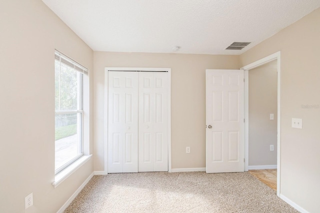 unfurnished bedroom with a closet, light colored carpet, and a textured ceiling