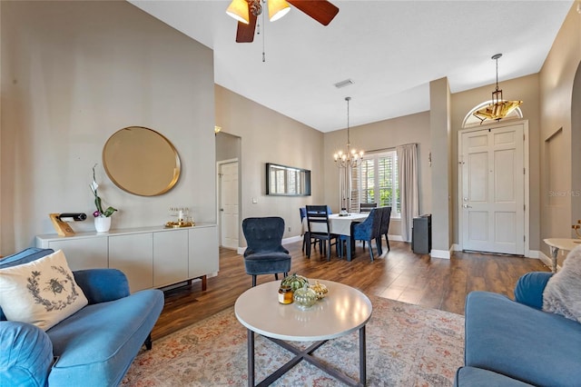 living room featuring ceiling fan with notable chandelier and dark wood-type flooring