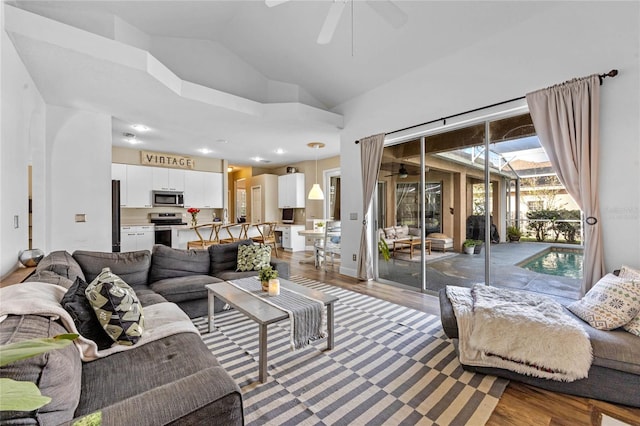 living room featuring dark hardwood / wood-style flooring, high vaulted ceiling, and ceiling fan