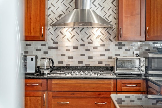 kitchen featuring tasteful backsplash, stainless steel gas stovetop, white fridge, and wall chimney range hood