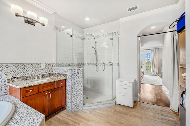 bathroom with wood-type flooring, vanity, independent shower and bath, and ornamental molding