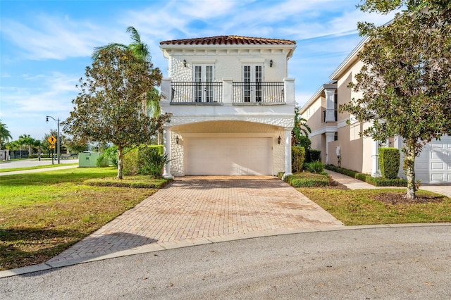 mediterranean / spanish home featuring a front lawn, a garage, a balcony, and french doors