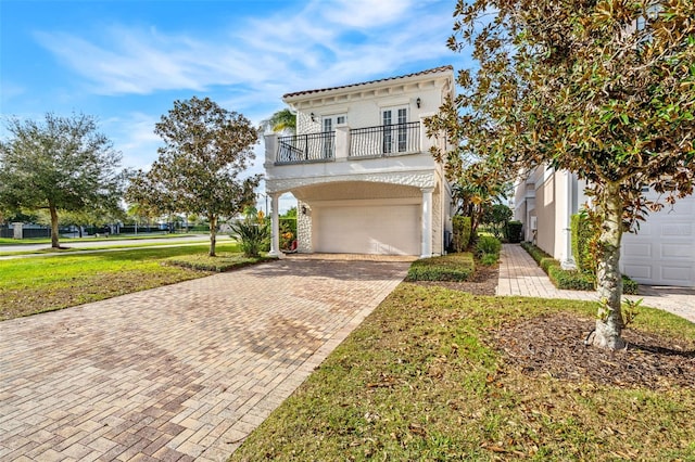 view of front of home featuring a garage, a balcony, a front yard, and french doors