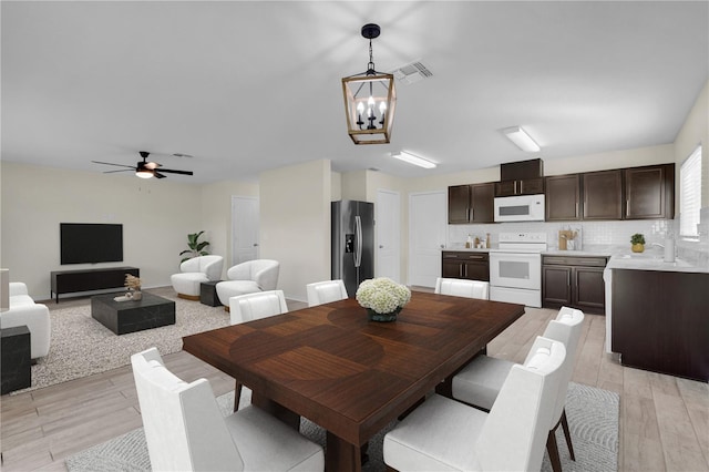 dining area featuring ceiling fan with notable chandelier and light hardwood / wood-style flooring