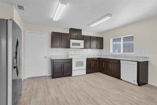 kitchen with dark brown cabinets, light hardwood / wood-style flooring, a textured ceiling, white appliances, and decorative backsplash