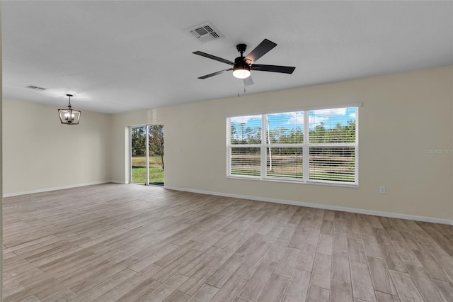 spare room with ceiling fan with notable chandelier and light hardwood / wood-style floors